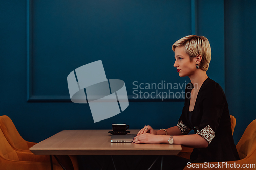 Image of Businesswoman sitting in a cafe while focused on working on a laptop and participating in an online meetings. Selective focus.