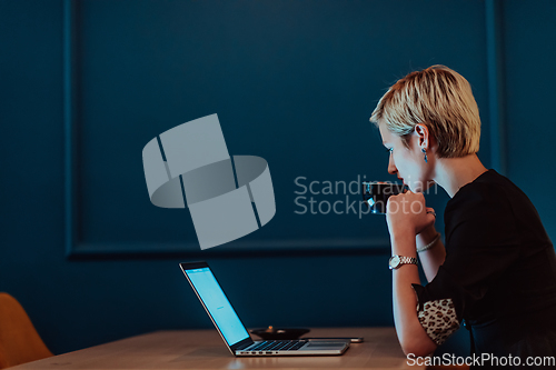 Image of Businesswoman sitting in a cafe while focused on working on a laptop and participating in an online meetings. Selective focus.