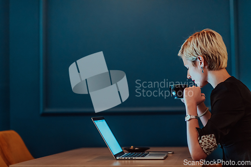 Image of Businesswoman sitting in a cafe while focused on working on a laptop and participating in an online meetings. Selective focus.