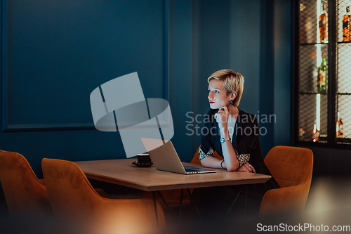 Image of Businesswoman sitting in a cafe while focused on working on a laptop and participating in an online meetings. Selective focus.