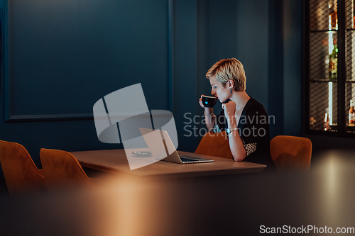 Image of Businesswoman sitting in a cafe while focused on working on a laptop and participating in an online meetings. Selective focus.