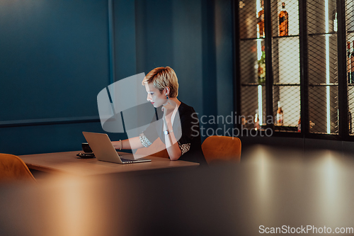 Image of Businesswoman sitting in a cafe while focused on working on a laptop and participating in an online meetings. Selective focus.