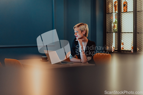 Image of Businesswoman sitting in a cafe while focused on working on a laptop and participating in an online meetings. Selective focus.