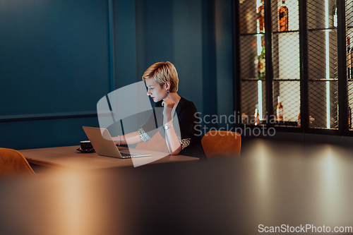 Image of Businesswoman sitting in a cafe while focused on working on a laptop and participating in an online meetings. Selective focus.