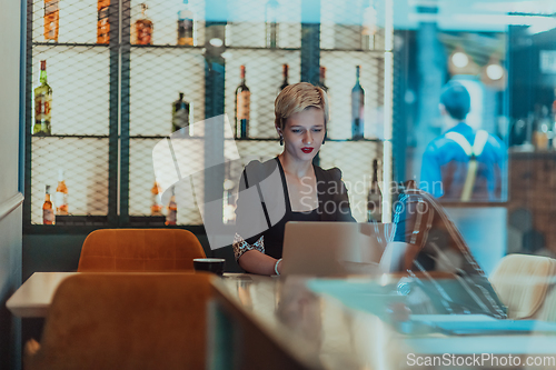 Image of Businesswoman sitting in a cafe while focused on working on a laptop and participating in an online meetings. Selective focus.