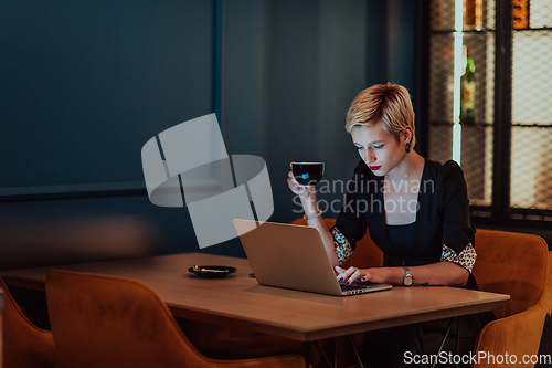 Image of Businesswoman sitting in a cafe while focused on working on a laptop and participating in an online meetings. Selective focus.