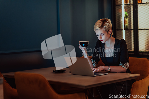 Image of Businesswoman sitting in a cafe while focused on working on a laptop and participating in an online meetings. Selective focus.