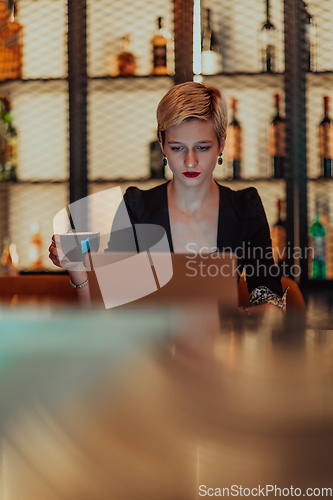 Image of Businesswoman sitting in a cafe while focused on working on a laptop and participating in an online meetings. Selective focus.
