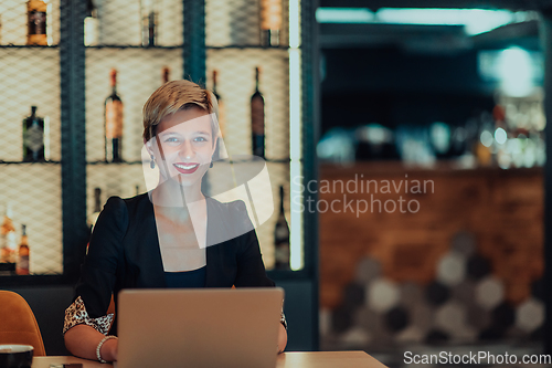 Image of Businesswoman sitting in a cafe while focused on working on a laptop and participating in an online meetings. Selective focus.