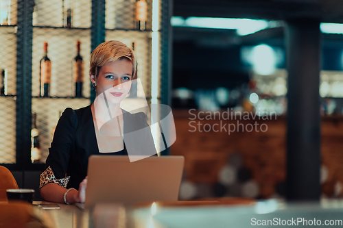 Image of Businesswoman sitting in a cafe while focused on working on a laptop and participating in an online meetings. Selective focus.