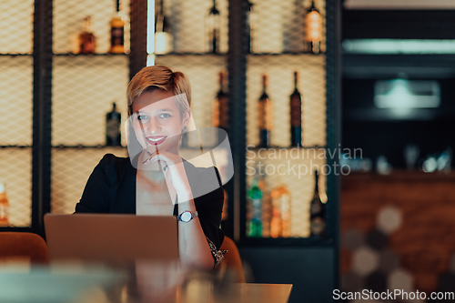 Image of Businesswoman sitting in a cafe while focused on working on a laptop and participating in an online meetings. Selective focus.