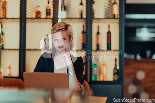 Image of Businesswoman sitting in a cafe while focused on working on a laptop and participating in an online meetings. Selective focus.