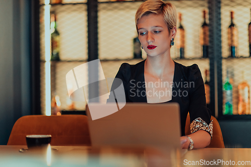 Image of Businesswoman sitting in a cafe while focused on working on a laptop and participating in an online meetings. Selective focus.