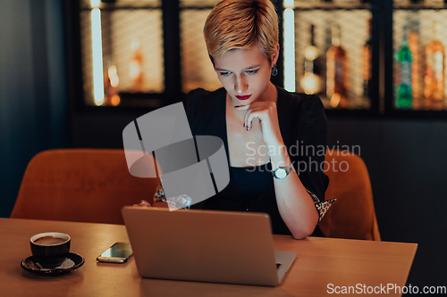 Image of Businesswoman sitting in a cafe while focused on working on a laptop and participating in an online meetings. Selective focus.