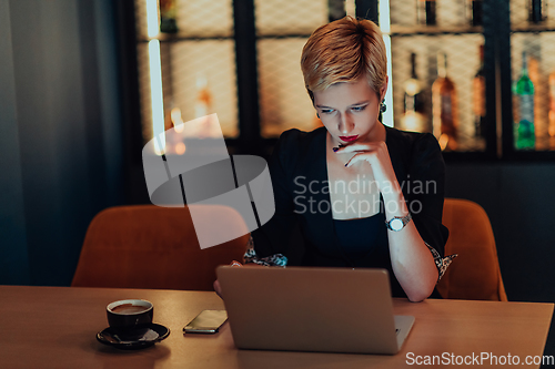 Image of Businesswoman sitting in a cafe while focused on working on a laptop and participating in an online meetings. Selective focus.