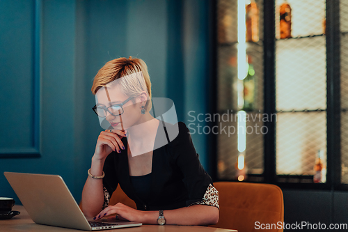 Image of Businesswoman sitting in a cafe while focused on working on a laptop and participating in an online meetings. Selective focus.