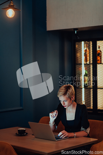 Image of Businesswoman sitting in a cafe while focused on working on a laptop and participating in an online meetings. Selective focus.