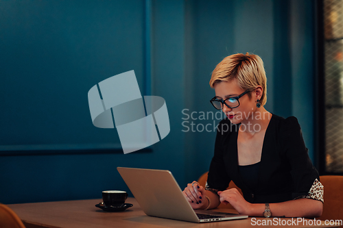 Image of Businesswoman sitting in a cafe while focused on working on a laptop and participating in an online meetings. Selective focus.