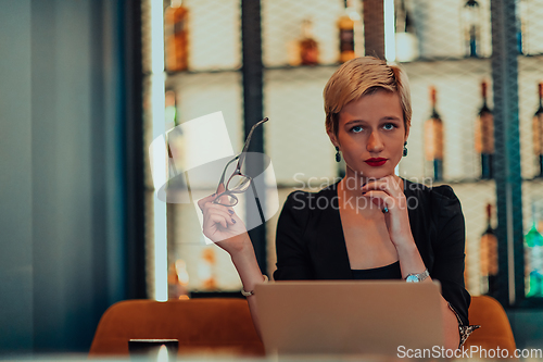 Image of Businesswoman sitting in a cafe while focused on working on a laptop and participating in an online meetings. Selective focus.
