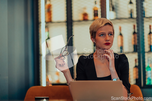 Image of Businesswoman sitting in a cafe while focused on working on a laptop and participating in an online meetings. Selective focus.