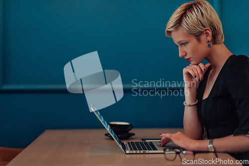 Image of Businesswoman sitting in a cafe while focused on working on a laptop and participating in an online meetings. Selective focus.