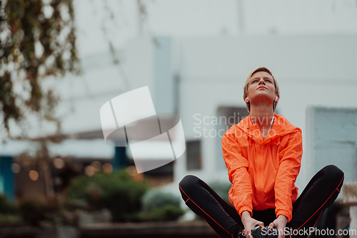 Image of Fit attractive woman in sportswear stretching one leg before jogging on the footpath outdoor in summer among greenery. Workout, sport, activity, fitness, vacation and training concept.