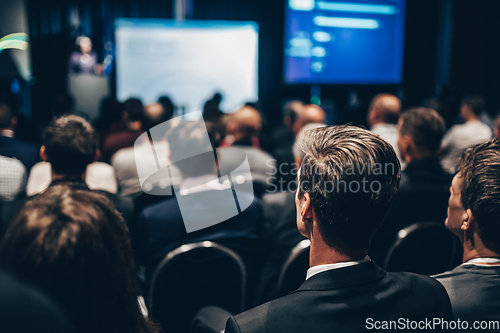 Image of Speaker giving a talk in conference hall at business event. Rear view of unrecognizable people in audience at the conference hall. Business and entrepreneurship concept.