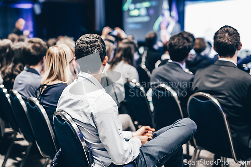 Image of Speaker giving a talk in conference hall at business event. Rear view of unrecognizable people in audience at the conference hall. Business and entrepreneurship concept.