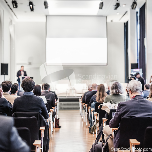 Image of Speaker giving a talk in conference hall at business event. Rear view of unrecognizable people in audience at the conference hall. Business and entrepreneurship concept.