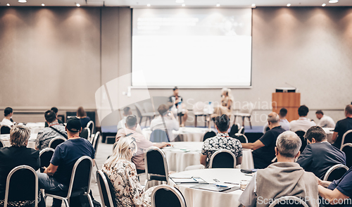 Image of Speaker giving a talk in conference hall at business event. Rear view of unrecognizable people in audience at the conference hall. Business and entrepreneurship concept.