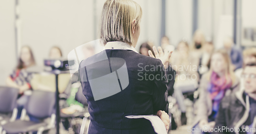 Image of Female public speaker giving talk at Business Event.