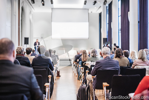 Image of Speaker giving a talk in conference hall at business event. Rear view of unrecognizable people in audience at the conference hall. Business and entrepreneurship concept.