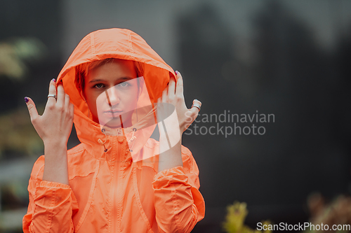 Image of a woman in a sports outfit is resting in a city environment after a hard morning workout while using noiseless headphones