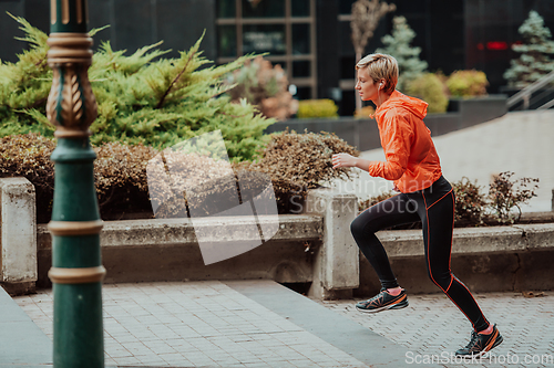 Image of A blonde in a sports outfit is running around the city in an urban environment. The hot blonde maintains a healthy lifestyle.