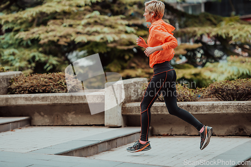Image of A blonde in a sports outfit is running around the city in an urban environment. The hot blonde maintains a healthy lifestyle.
