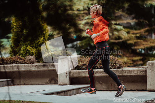 Image of A blonde in a sports outfit is running around the city in an urban environment. The hot blonde maintains a healthy lifestyle.