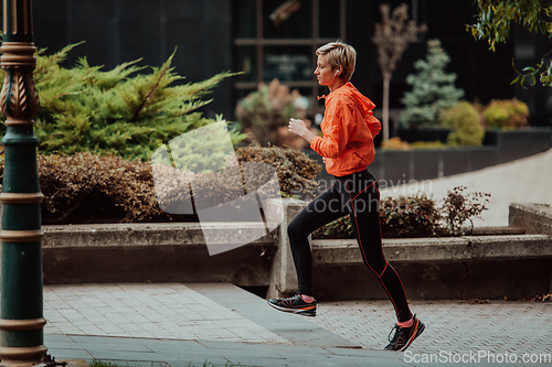 Image of A blonde in a sports outfit is running around the city in an urban environment. The hot blonde maintains a healthy lifestyle.