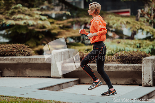 Image of A blonde in a sports outfit is running around the city in an urban environment. The hot blonde maintains a healthy lifestyle.