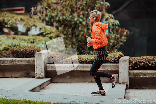 Image of A blonde in a sports outfit is running around the city in an urban environment. The hot blonde maintains a healthy lifestyle.