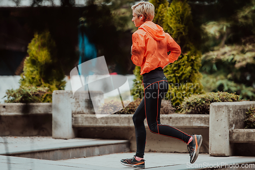 Image of A blonde in a sports outfit is running around the city in an urban environment. The hot blonde maintains a healthy lifestyle.