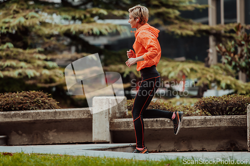 Image of A blonde in a sports outfit is running around the city in an urban environment. The hot blonde maintains a healthy lifestyle.