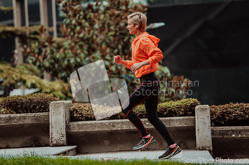 Image of A blonde in a sports outfit is running around the city in an urban environment. The hot blonde maintains a healthy lifestyle.