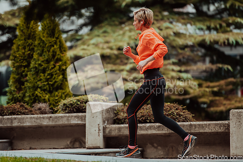 Image of A blonde in a sports outfit is running around the city in an urban environment. The hot blonde maintains a healthy lifestyle.