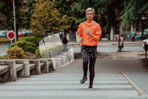 Image of A blonde in a sports outfit is running around the city in an urban environment. The hot blonde maintains a healthy lifestyle.