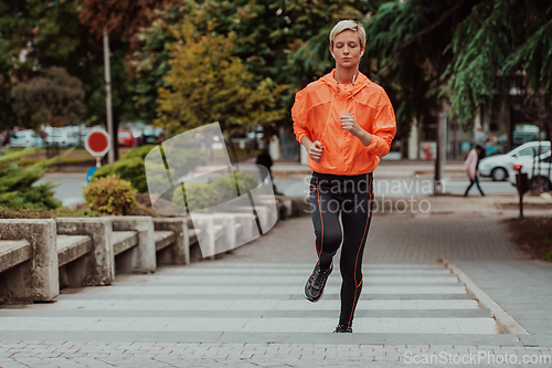 Image of A blonde in a sports outfit is running around the city in an urban environment. The hot blonde maintains a healthy lifestyle.