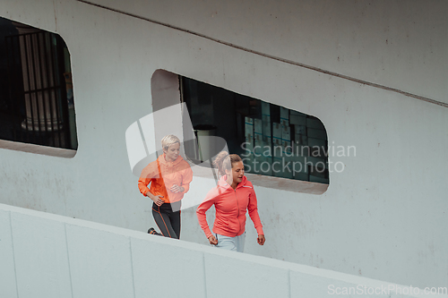 Image of Two women in sports clothes running in a modern urban environment. The concept of a sporty and healthy lifestyle