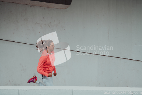 Image of Women in sports clothes running in a modern urban environment. The concept of a sporty and healthy lifestyle