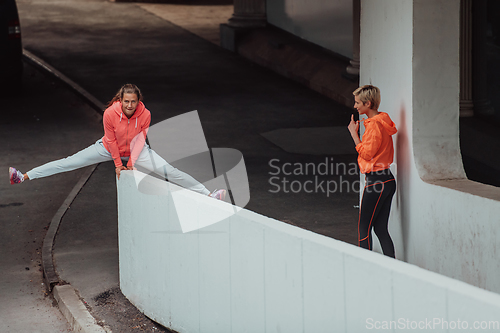 Image of Two women in sports clothes running in a modern urban environment. The concept of a sporty and healthy lifestyle