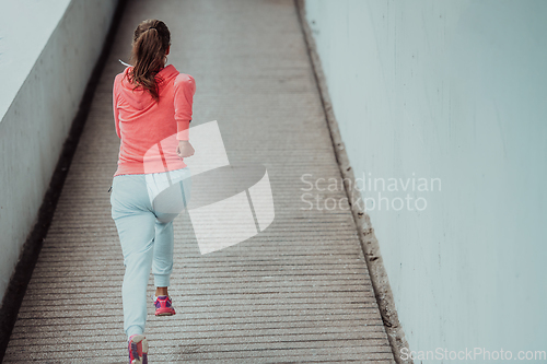 Image of Women in sports clothes running in a modern urban environment. The concept of a sporty and healthy lifestyle