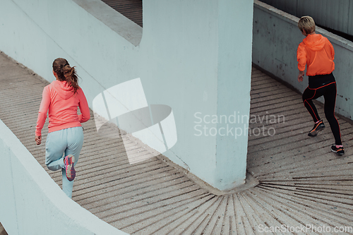 Image of Two women in sports clothes running in a modern urban environment. The concept of a sporty and healthy lifestyle